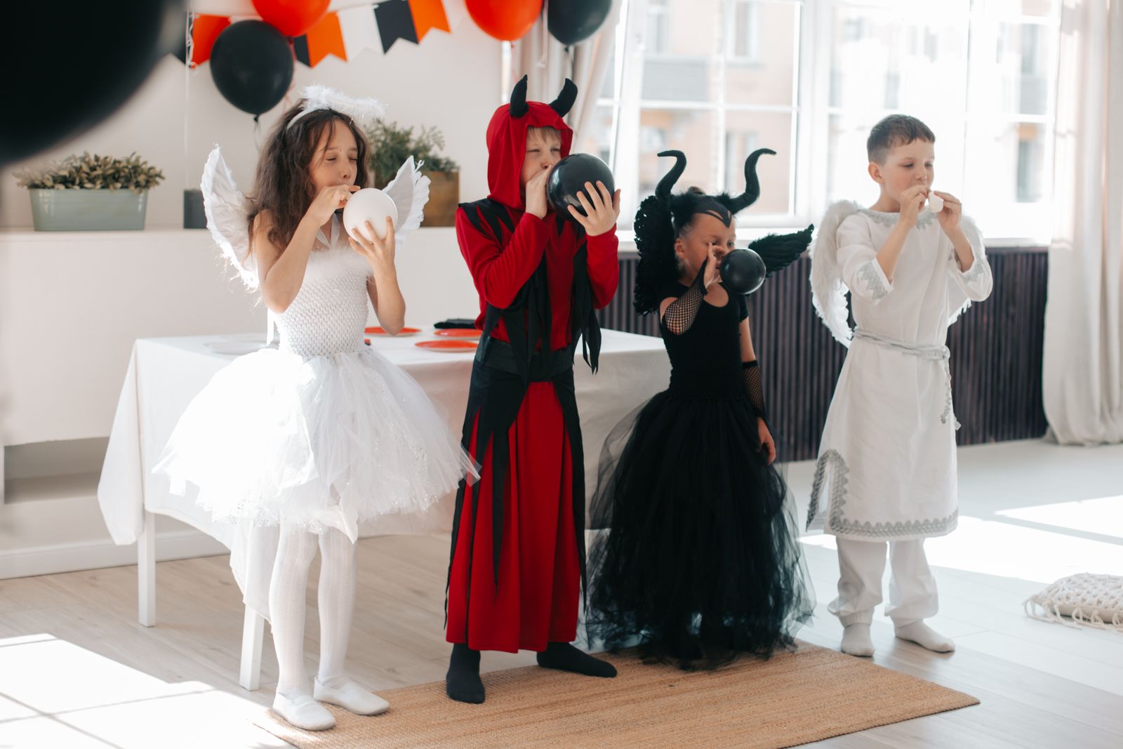 Halloweeni pidu kostüümides Halloweeni peo külalised kostüümides heledas saalis oranžide ja mustade õhupallidega